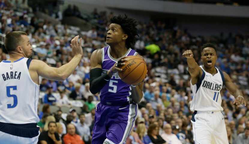 Sacramento Kings guard De'Aaron Fox (5) drives between Dallas Mavericks guards J.J. Barea...