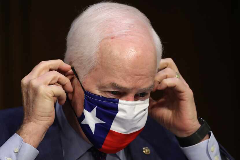 El senador por el estado de Texas, John Cornyn, se ajusta su cubrebocas durante una sesión...