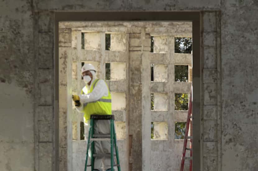 A worker removes paint as Phase II of renovations of Dealey Plaza continue on the pergola on...
