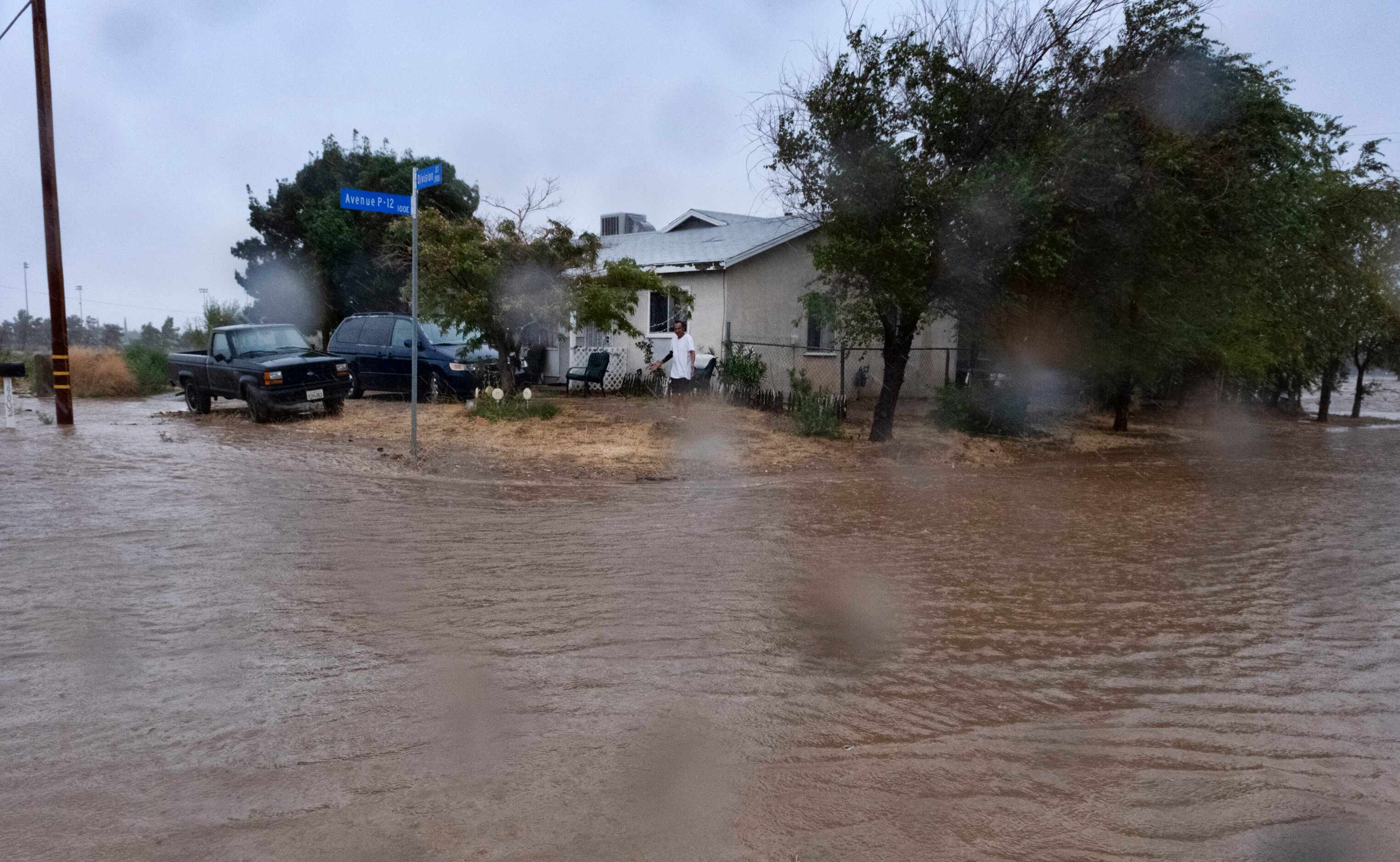 A resident checks the floodwaters surrounding his home during a downpour in Palmdale,...
