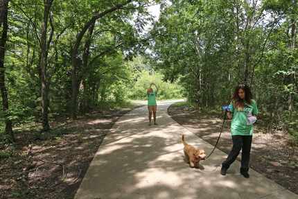 Dana McCormick (background) takes a photo as Diana Nowlin walks McCormick's dog Romero along...