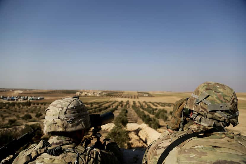 In this Feb. 7, 2018 file photo, American troops look out toward the border with Turkey from...