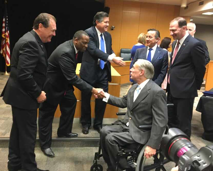 Gov. Greg Abbott, foreground right,  shown shaking hands with executive commissioner of...