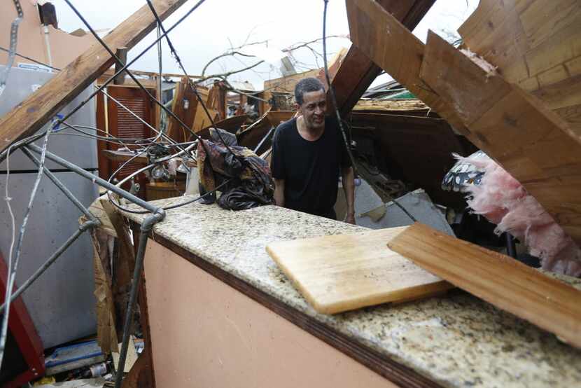 Gregory Rugon looks for his glasses at the spot where he took cover in his home after a...