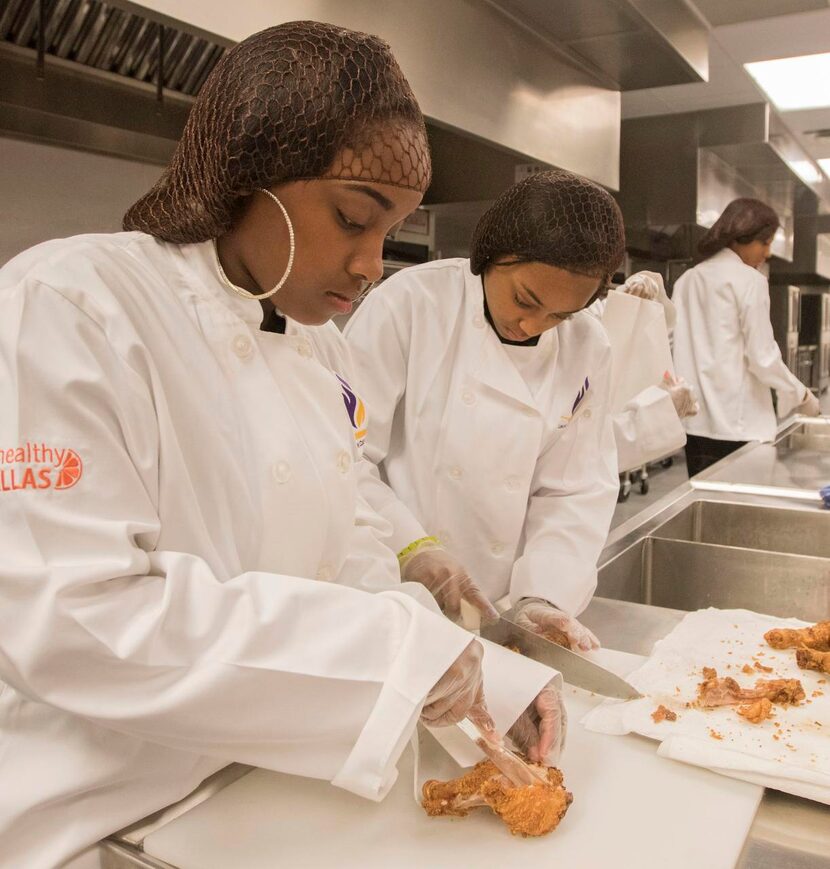 Sherica Davis  (left) and Kameran Thomas, cut up chicken.