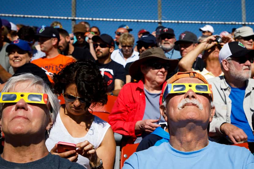 Fans watch a total solar eclipse during a minor league baseball game between the...