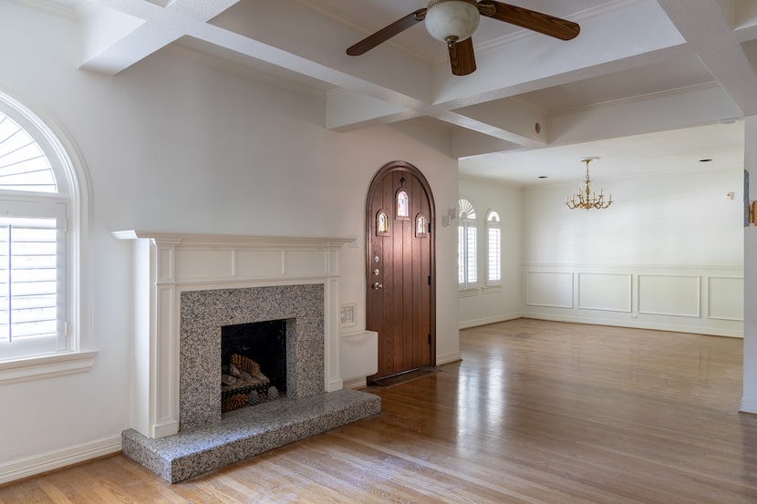 Bare living room with polished hardwood floors, white walls and a gray stone fireplace