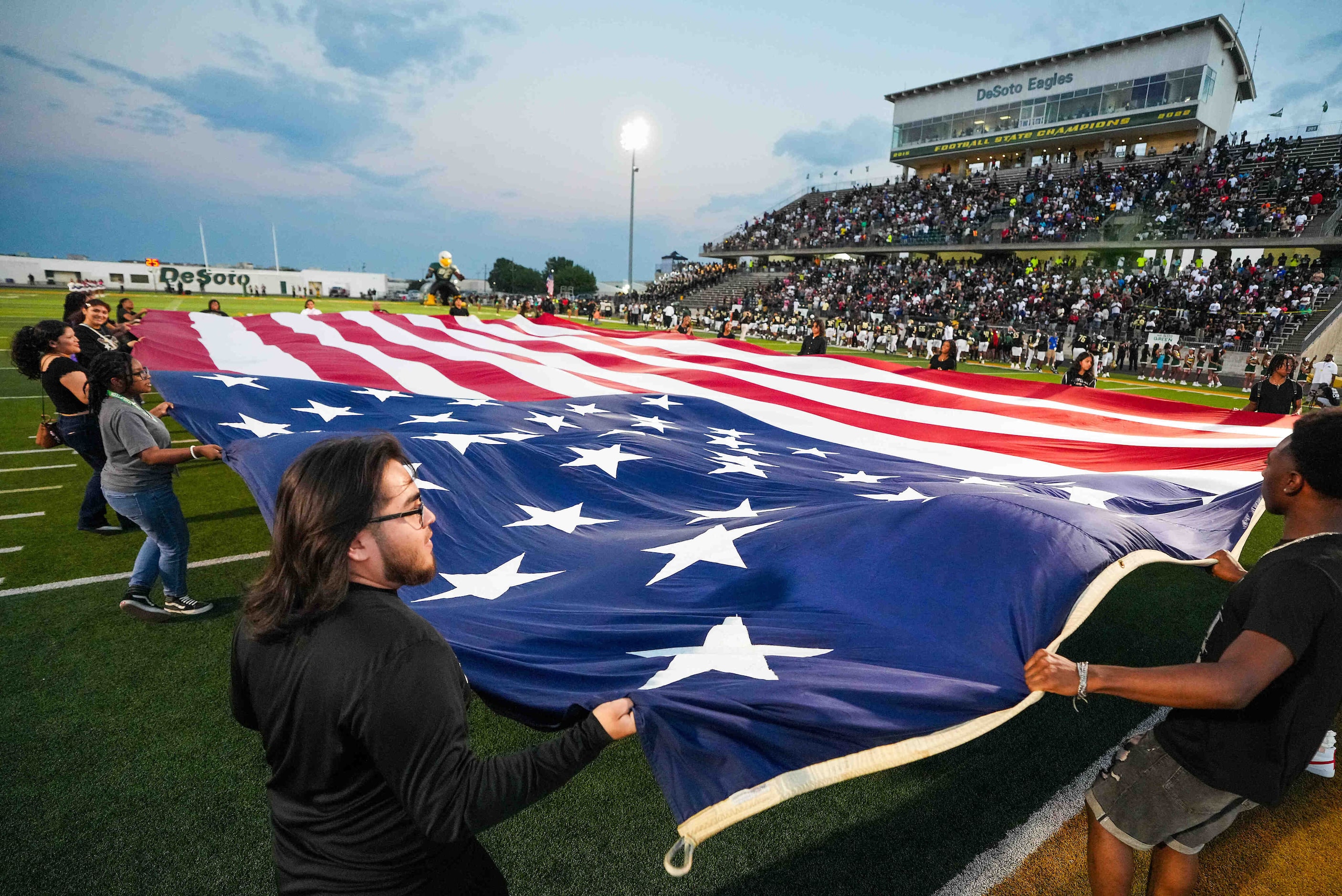 Members of the DeSoto JROTC carry a large flag across the field during the national anthem...