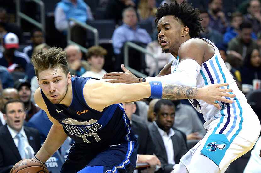 The Dallas Mavericks' Luka Doncic, left, drives to the basket around the Charlotte Hornets'...