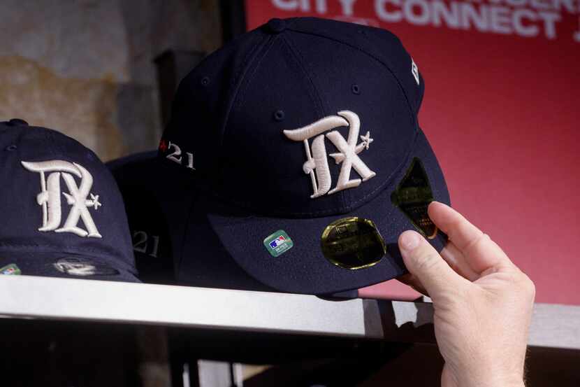 A Texas Rangers fan reaches for a new City Connect baseball hat at Globe Life Field on...
