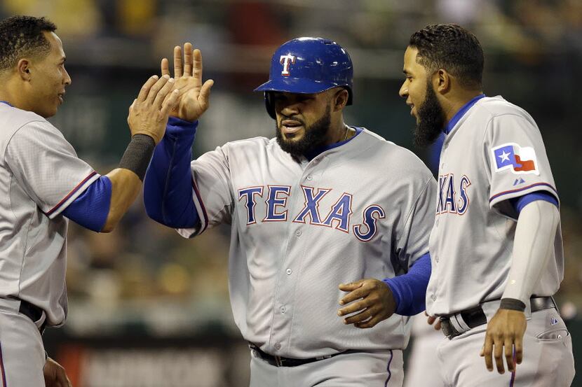 Texas Rangers' Prince Fielder, center, is congratulated by Leonys Martin, left, and Elvis...