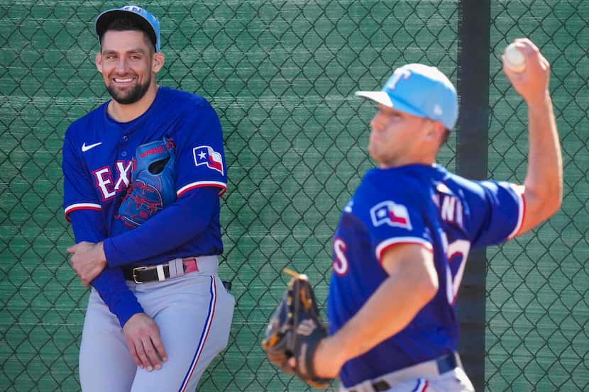 Texas Rangers pitcher Cole Winn throws in the bullpen as pitcher Nathan Eovaldi looks on...