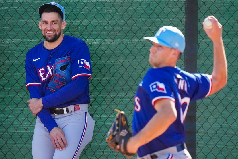 Texas Rangers pitcher Cole Winn throws in the bullpen as pitcher Nathan Eovaldi looks on...