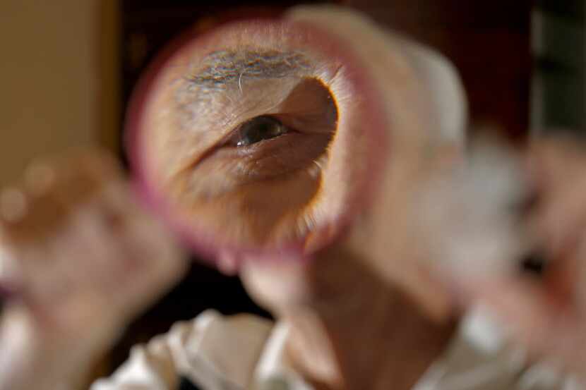 Amateur rock collector John Tackel poses for a photograph with a magnifier at his apartment...