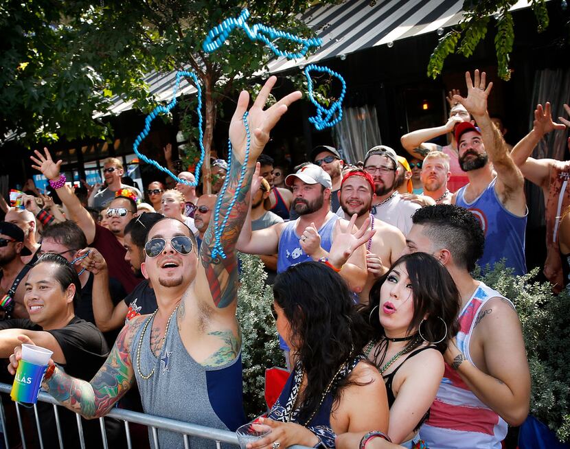 People reach for beads thrown from passing floats during the Texas Freedom Parade, Sunday,...