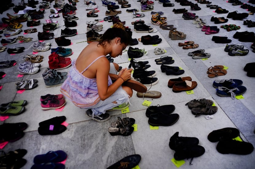 A woman places one of the hundreds of shoes in memory of those killed by Hurricane Maria in...