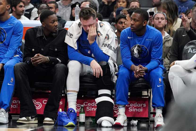 Dallas Mavericks guard Luka Doncic, center, sits on the bench during the first half of an...