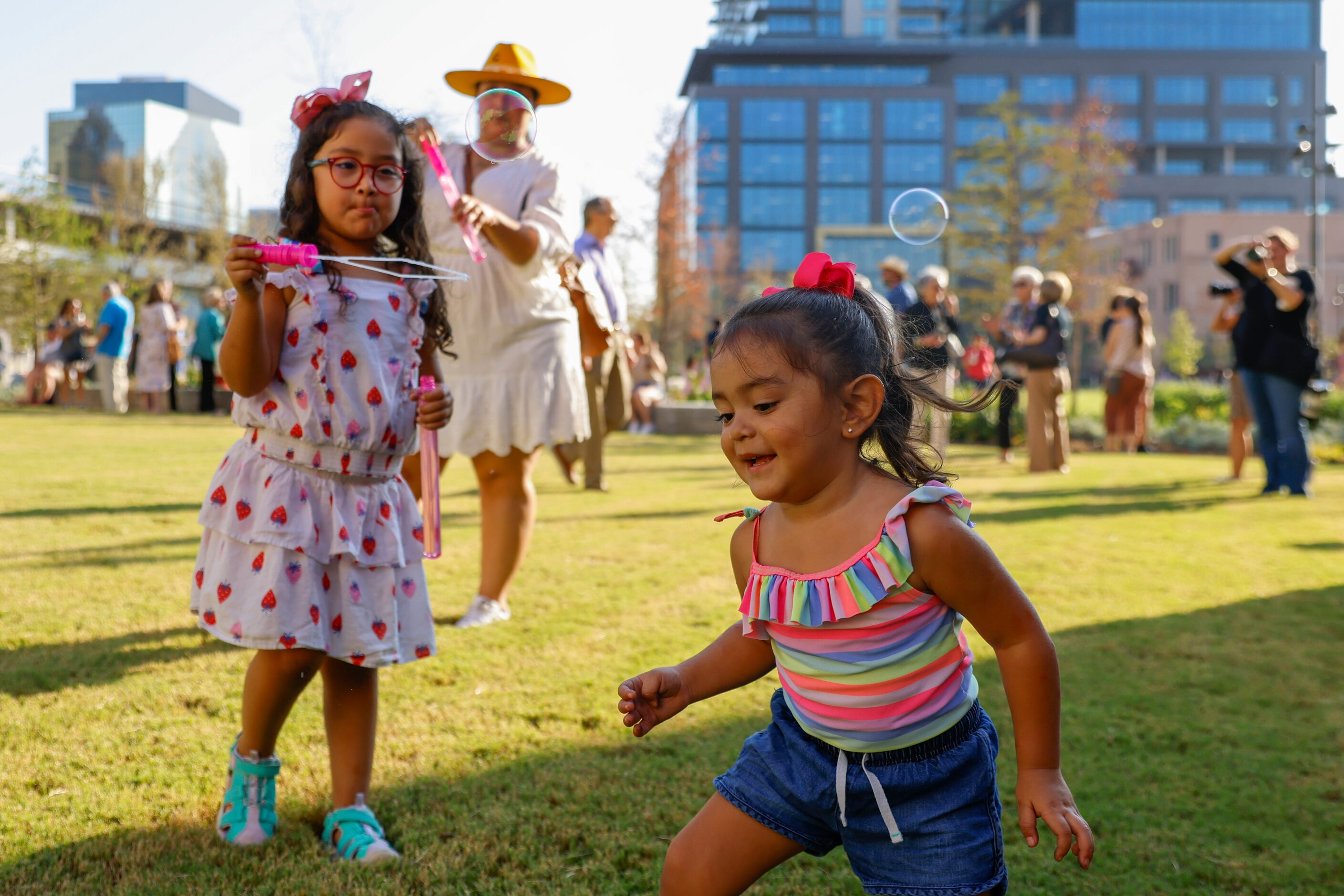 Ava Moreno, (left), 5, blows soap bubble as Noelle Huerta, 2, plays on the open lawn during...