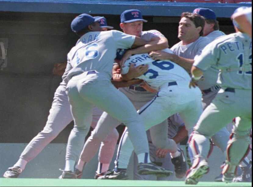 Kansas City Royals' Brian McRae, center, is tackled by members of the Texas Rangers...