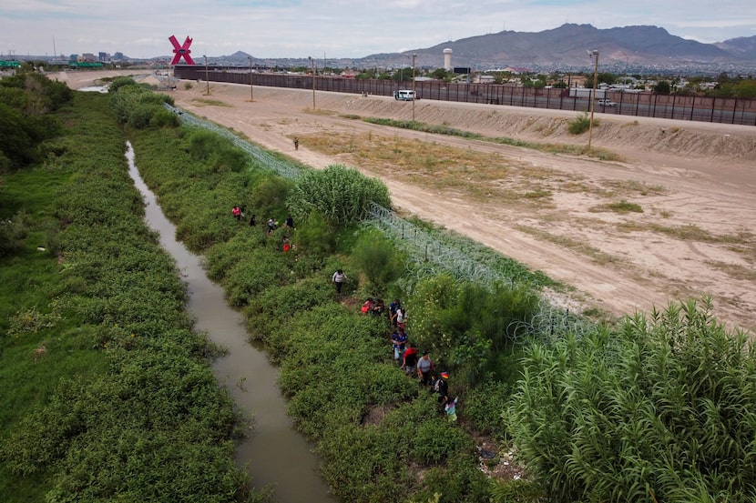 Migrants arriving in Juarez seek refuge along the banks of the Rio Grande near the towering...