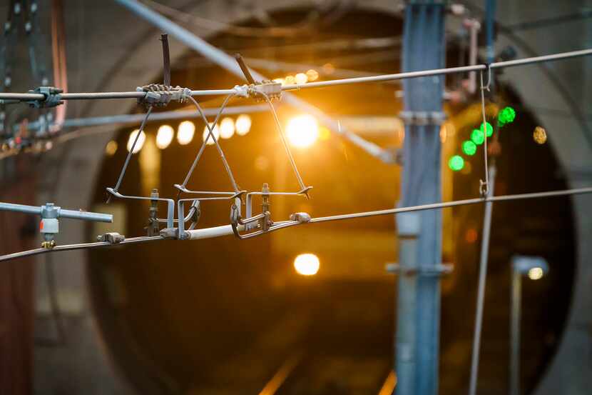 A DART rail train passes under overhead power lines as it arrives at Mockingbird Station on...