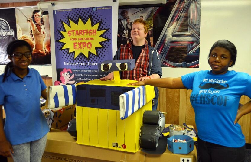 
Alandria Rivera (left), John David Kinneman and Shatequa Driver stand by a paper Wall-E...