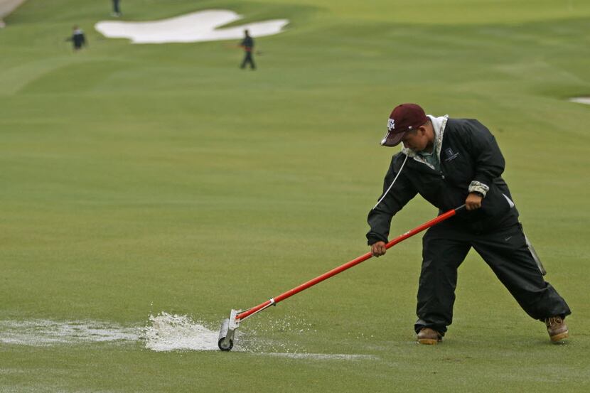 Workers squeegy the course on Hole No. 1 after morning rain delays on day one of the Byron...