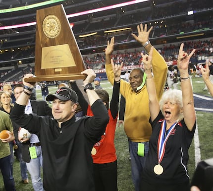 Cedar Hill head coach Joey McGuire hoists the UIL trophy after their 34-24 win for the state...