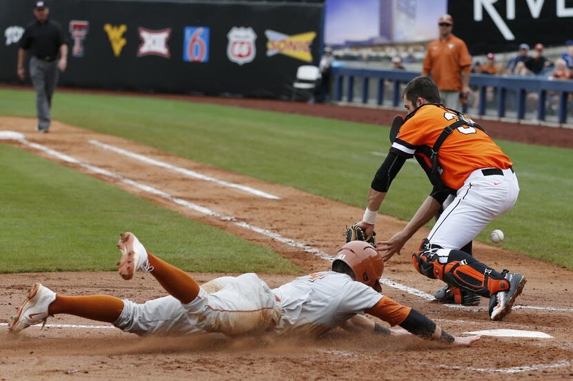 Texas' Ben Johnson (14) slides safely into home plate as the ball gets away from Oklahoma...