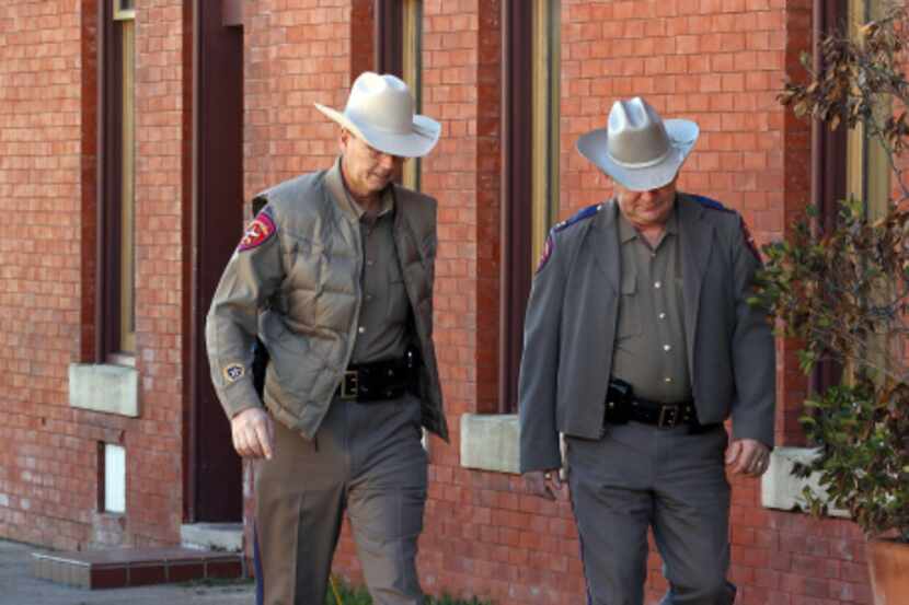 Texas state troopers walk past evidence markers placed by investigators at the scene were...