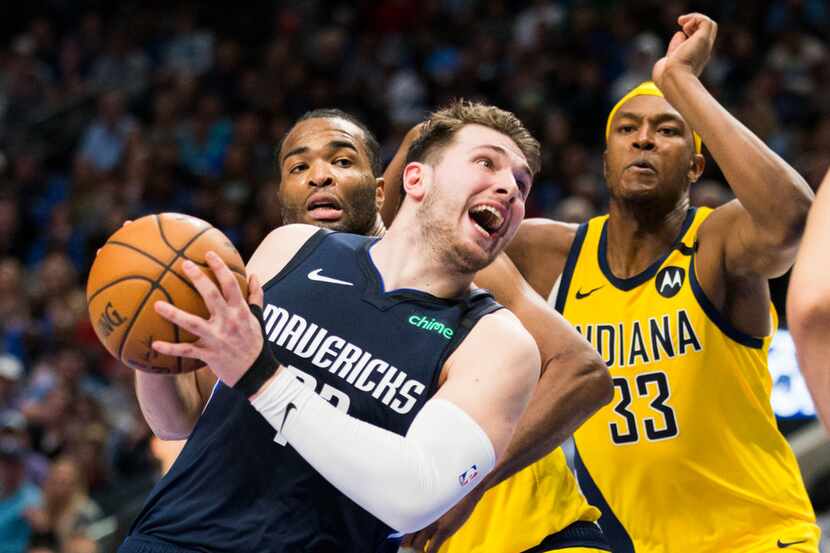 FILE - Mavericks guard Luka Doncic (77) is fouled by Pacers forward T.J. Warren (1) during...
