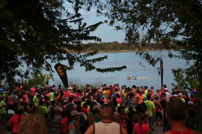 A rower heads across White Rock Lake as runners wait for the start of the 10k race during...