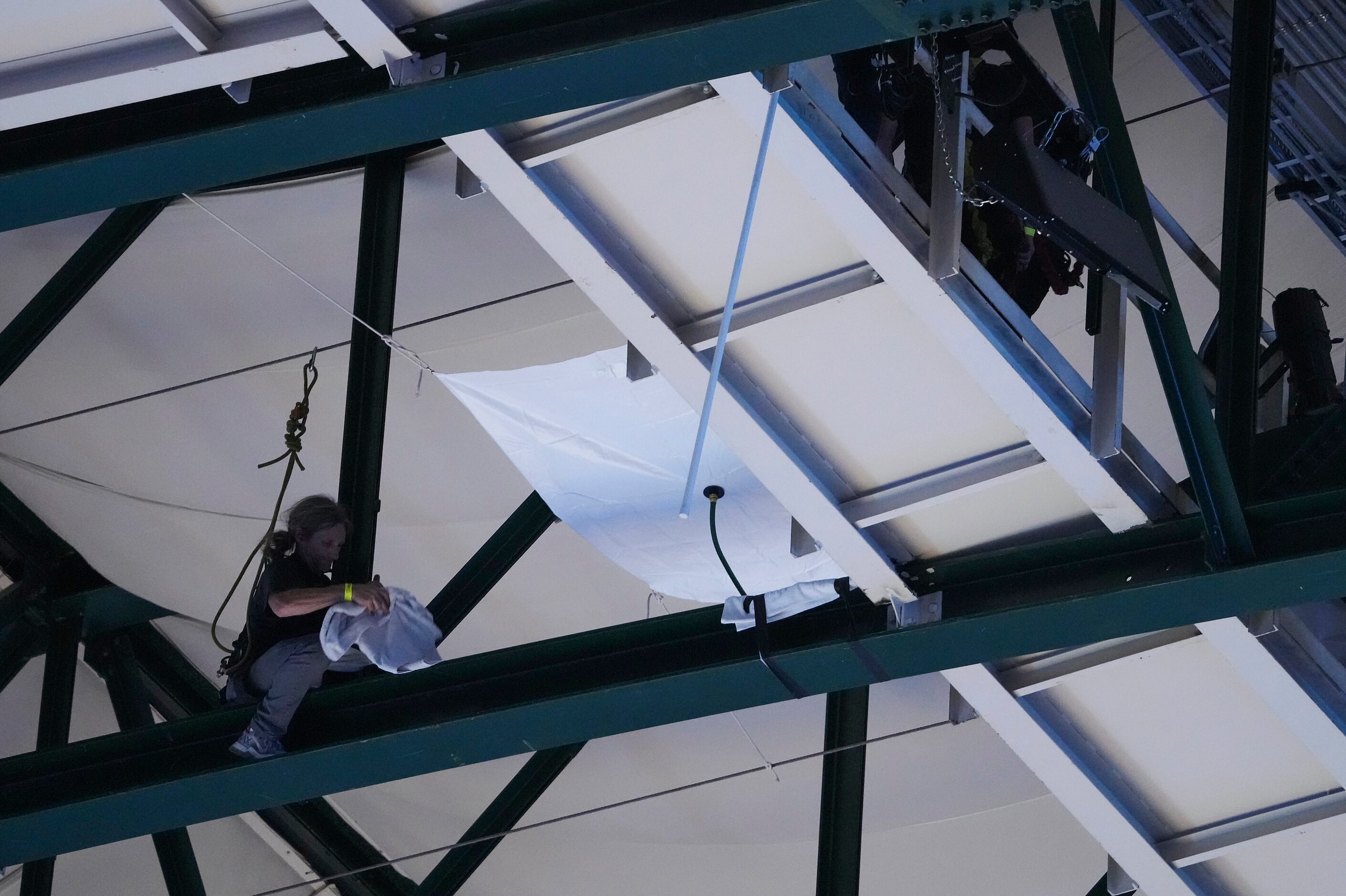 Arena workers are seen in the catwalk trying to contain water from a leaking room during...