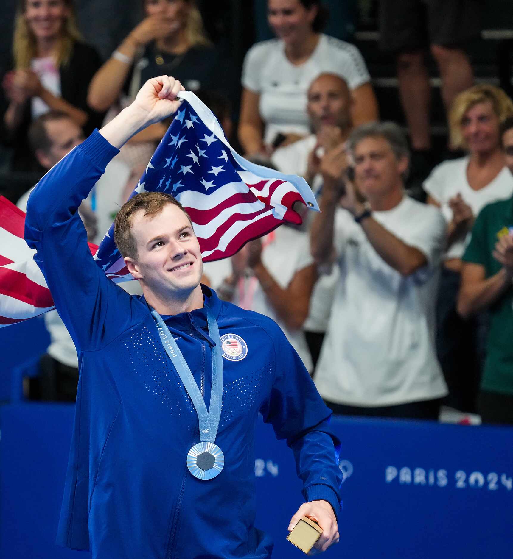 Nic Fink of the United States waves the American flag as he celebrates with fans after...