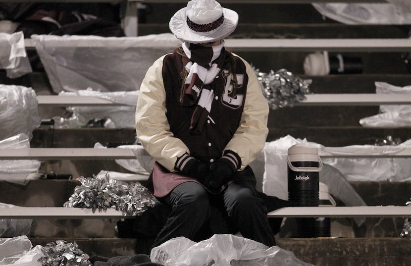A member of the Ennis High School drill team sits in the stands in the second half of the...