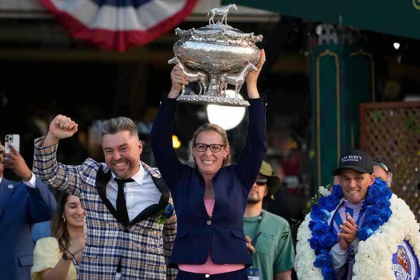 Trainer Jena Antonucci, center, hoists up the August Belmont Trophy alongside jockey Javier...