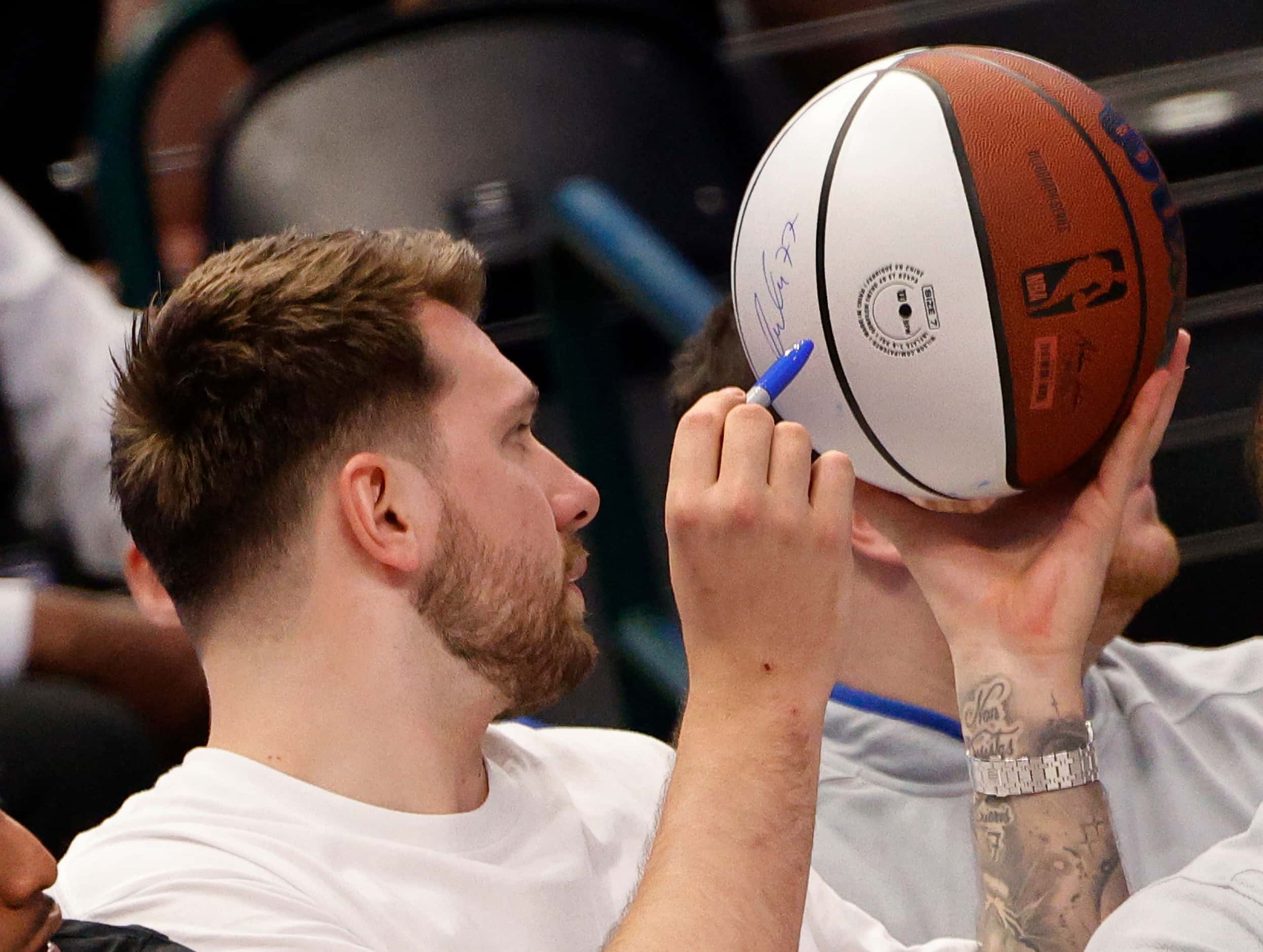 Dallas Mavericks guard Luka Doncic (77) signs his autograph on a ball for a fan during the...