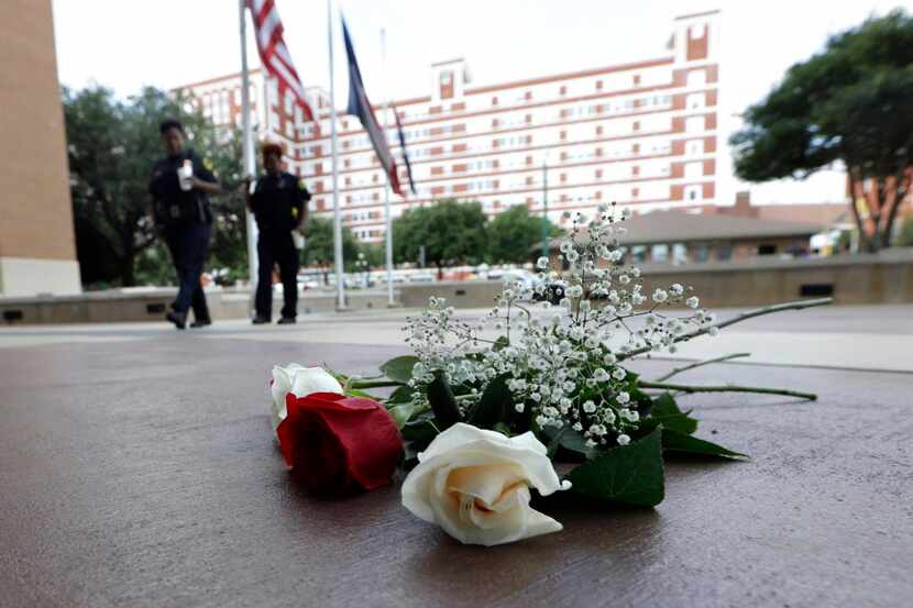 In this July 8, 2016, file photo, police officers walk past roses left at the front doors of...