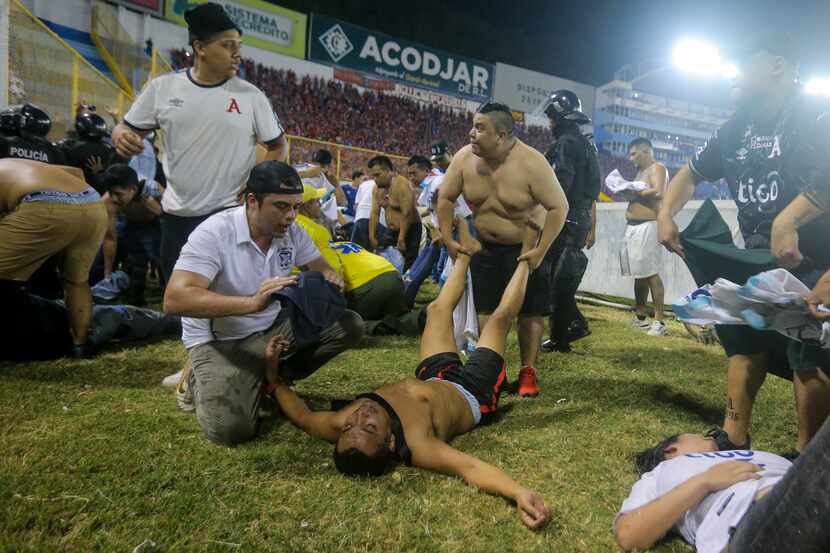 Aficionados al fútbol atienden en la cancha a los heridos por una estampida humana en el...
