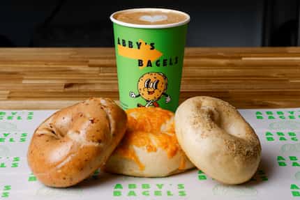 Abby's Bagels sells coffees in a bright green cup with a cartoon bagel.