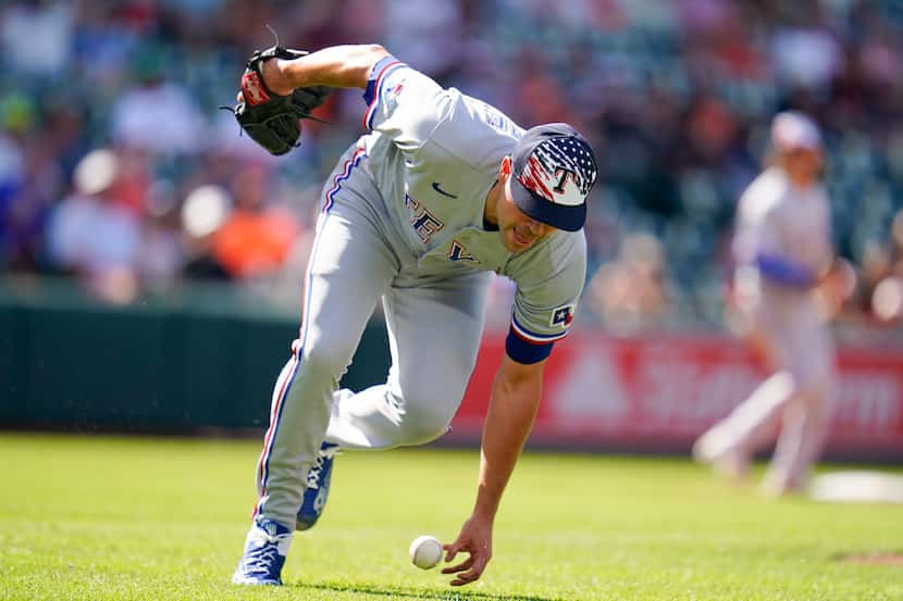Texas Rangers relief pitcher Matt Moore is unable to handle a bunt single by Baltimore...