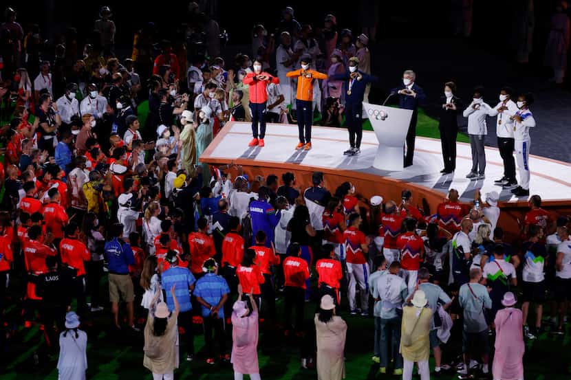 IOC president Thomas Bach signals a heart with others after giving his speech during the...