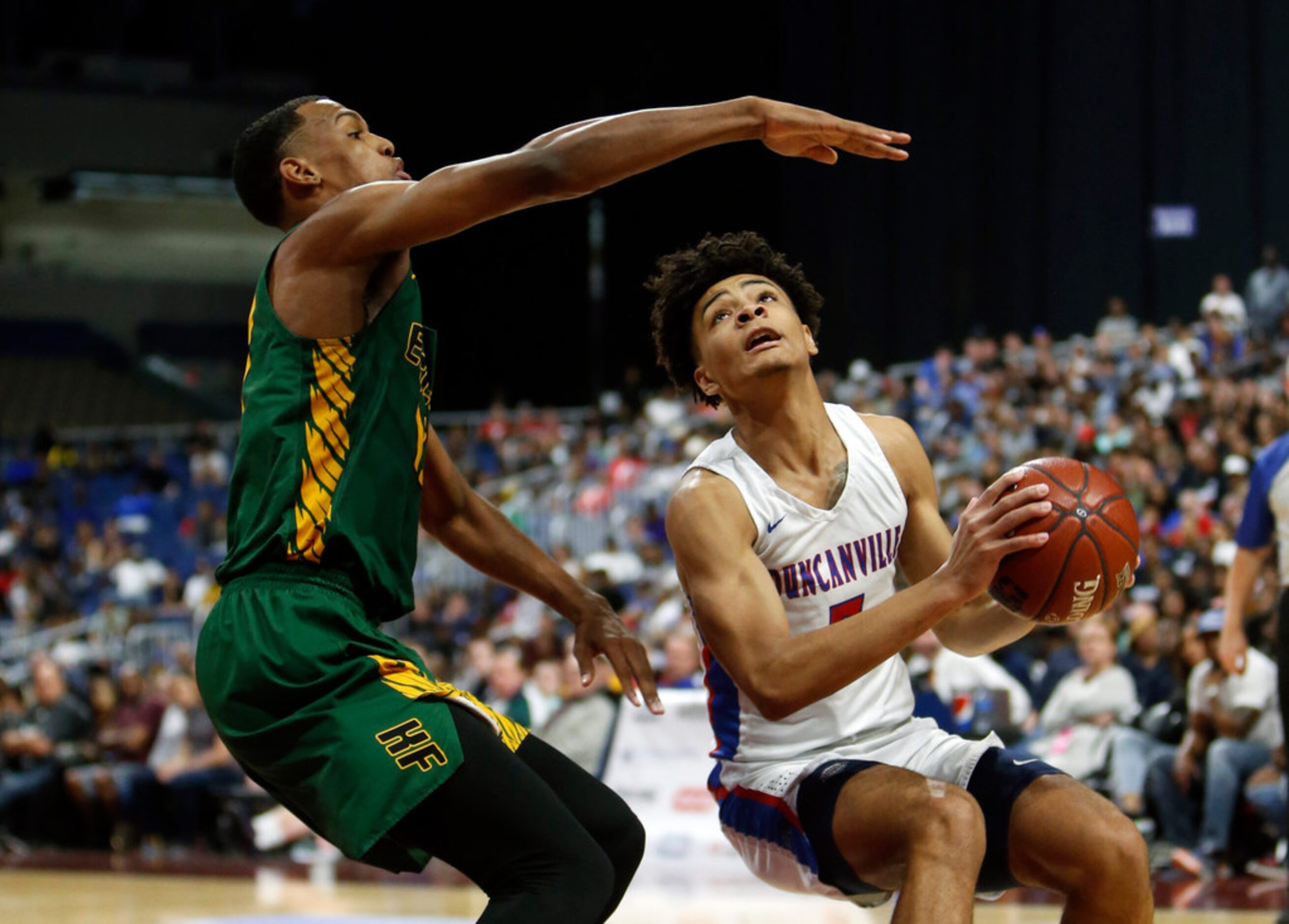 Duncanville's Micah Peavy #5 drives under Klein Forest's Calvin Solomon #13 during a UIL...