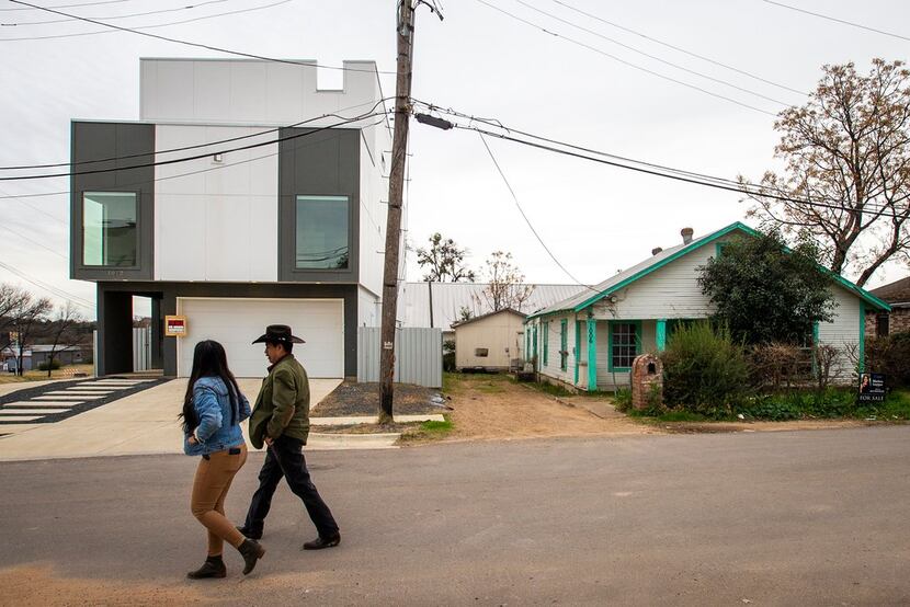 Elizabeth Garcia and father Leonardo Garcia walk past new and old homes in their West Dallas...