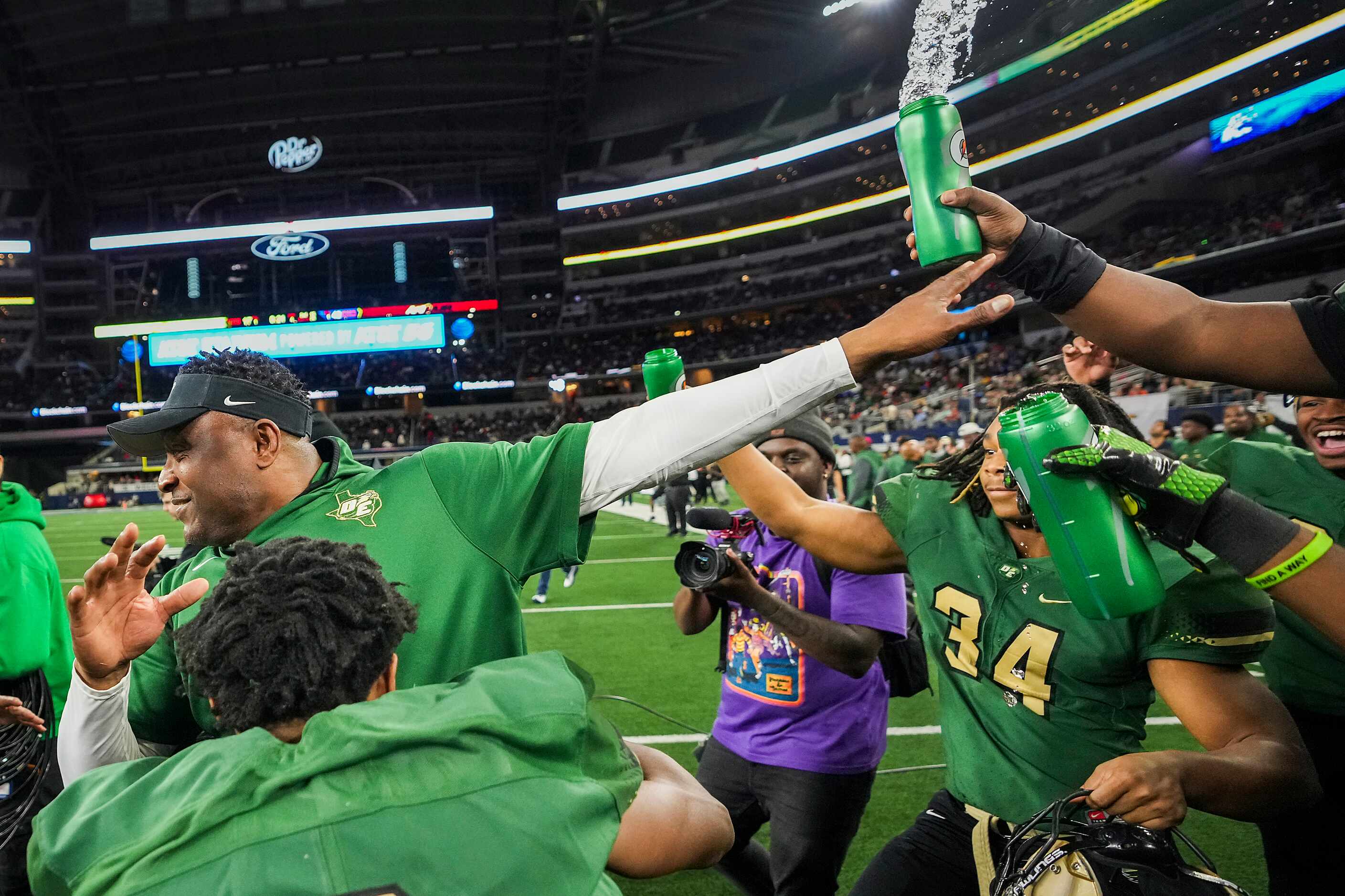 DeSoto head coach Claude Mathis is doused with water bottles by his players after a victory...