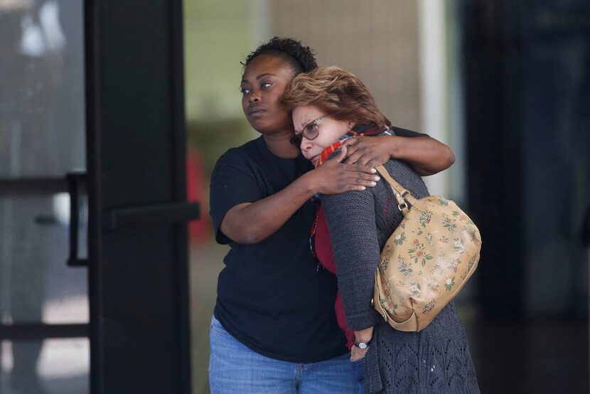 Two women embrace at a community center where family members are gathering to pick up...