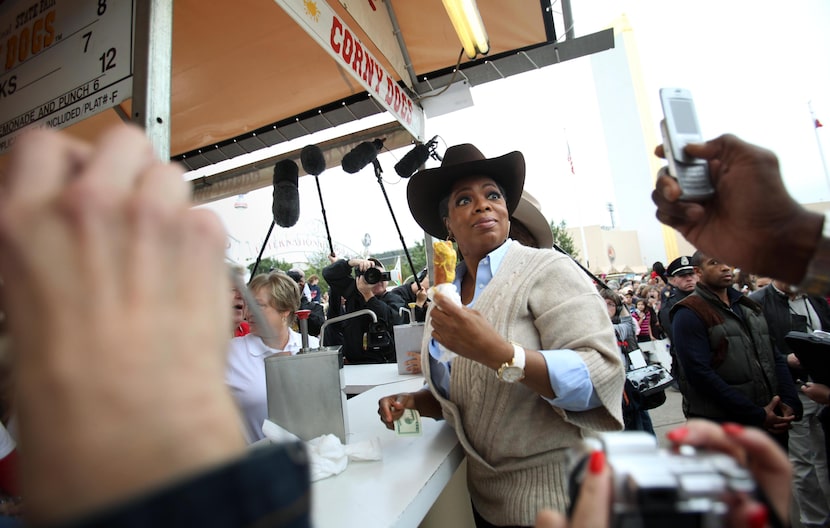 Oprah Winfrey looks back at the crowd while eating a corny dog with mustard at the State...