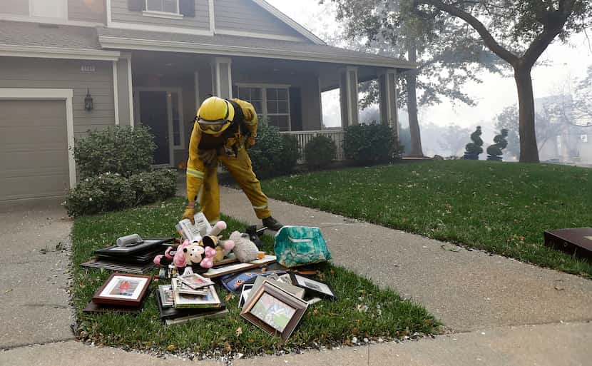 A Santa Rosa firefighter places belongings onto the lawn of a home in Santa Rosa, Calif.,...