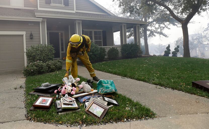 A Santa Rosa firefighter places belongings onto the lawn of a home in Santa Rosa, Calif.,...