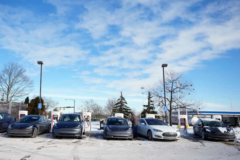 Teslas lined up at a charging station Wednesday in Ann Arbor, Mich., as EV owners...